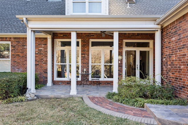 entrance to property featuring a shingled roof and brick siding