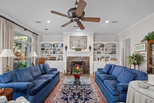 living area with visible vents, a premium fireplace, built in features, and crown molding