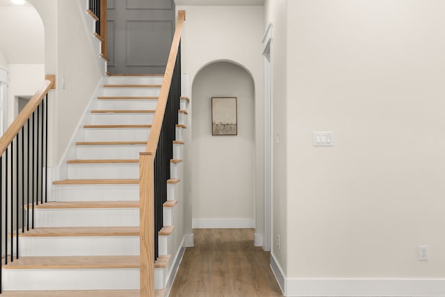 staircase featuring wood finished floors and baseboards