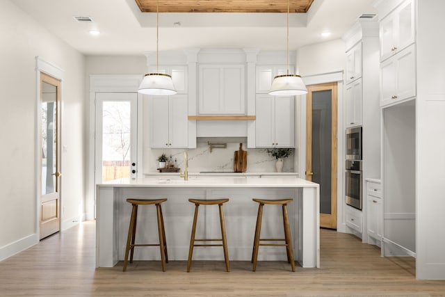 kitchen featuring white cabinetry, a tray ceiling, light countertops, and backsplash