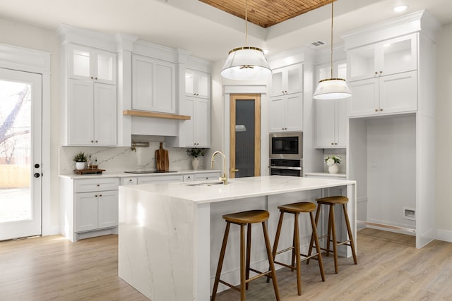 kitchen with visible vents, a raised ceiling, black electric stovetop, built in microwave, and a sink