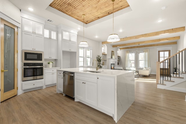 kitchen with a sink, visible vents, appliances with stainless steel finishes, light wood finished floors, and a raised ceiling