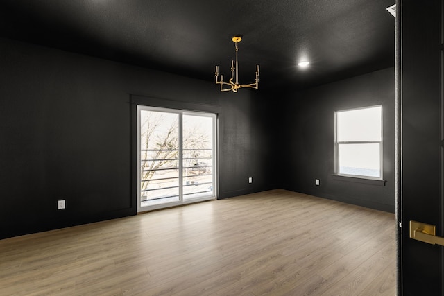 empty room featuring a chandelier, a textured ceiling, and wood finished floors