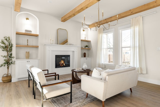 living room featuring wood finished floors, beamed ceiling, and a glass covered fireplace