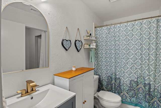 full bath featuring a textured wall, curtained shower, toilet, visible vents, and vanity