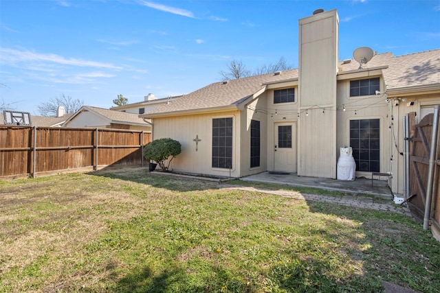 back of house featuring fence, a yard, roof with shingles, a chimney, and a patio area