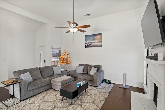 living room with wood finished floors, visible vents, baseboards, a ceiling fan, and a brick fireplace