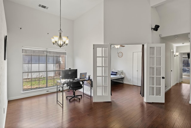 office area with french doors, visible vents, a high ceiling, an inviting chandelier, and wood finished floors