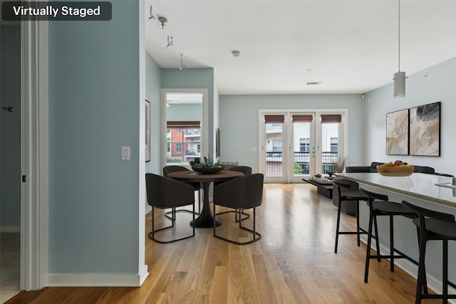 dining area featuring baseboards, light wood-type flooring, visible vents, and a wealth of natural light