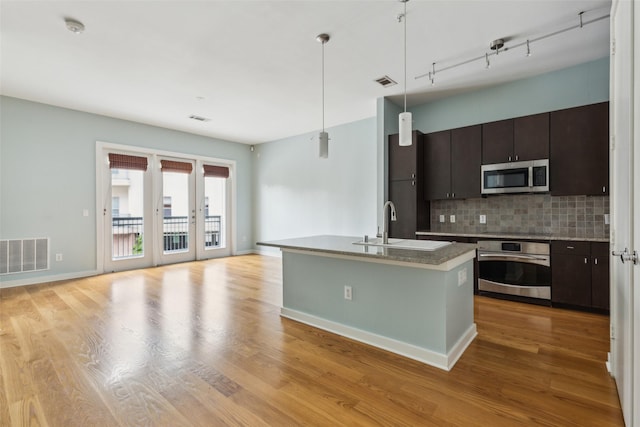 kitchen with visible vents, stainless steel appliances, a sink, and decorative backsplash