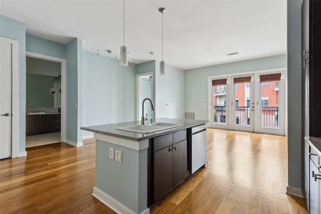 kitchen with a sink, visible vents, dishwasher, wood finished floors, and an island with sink