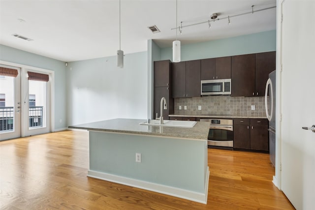 kitchen featuring visible vents, appliances with stainless steel finishes, light wood finished floors, and a sink