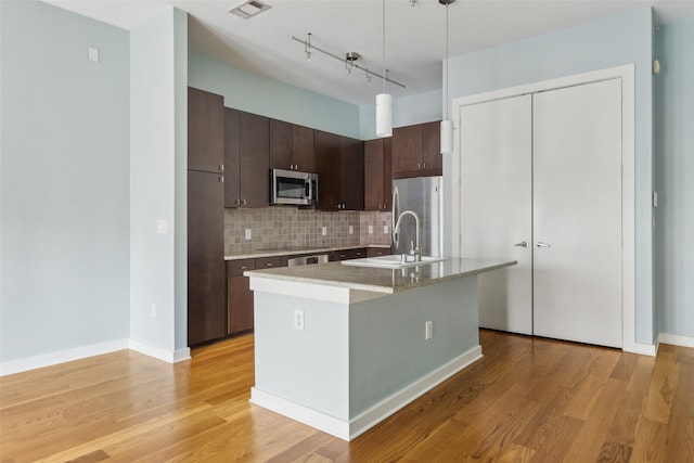 kitchen with a sink, appliances with stainless steel finishes, visible vents, light countertops, and dark brown cabinets