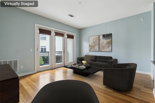 living area with baseboards, visible vents, and wood finished floors