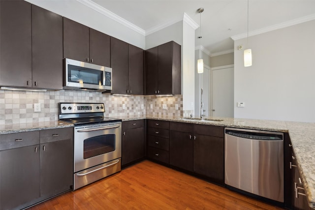 kitchen with ornamental molding, light wood-style flooring, stainless steel appliances, and tasteful backsplash