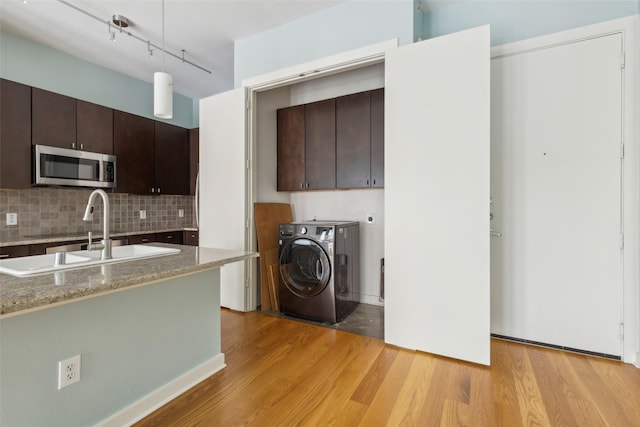 laundry room featuring a sink, light wood finished floors, separate washer and dryer, and cabinet space