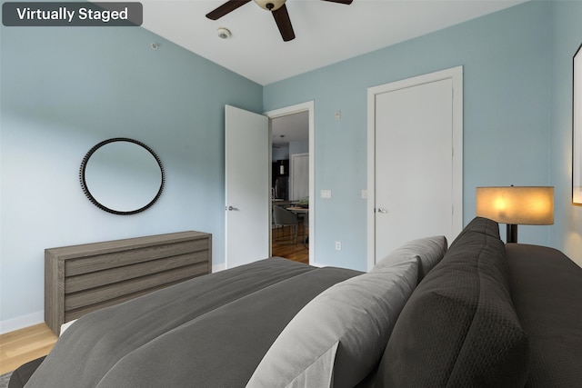 bedroom with ceiling fan, wood finished floors, and baseboards