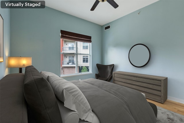 bedroom featuring a ceiling fan, visible vents, wood finished floors, and baseboards