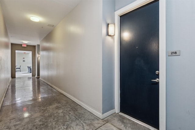hallway featuring finished concrete floors and baseboards