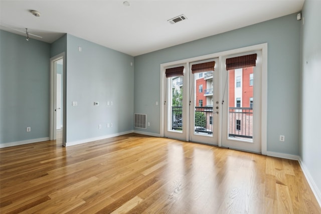 unfurnished room featuring wood finished floors, visible vents, and baseboards