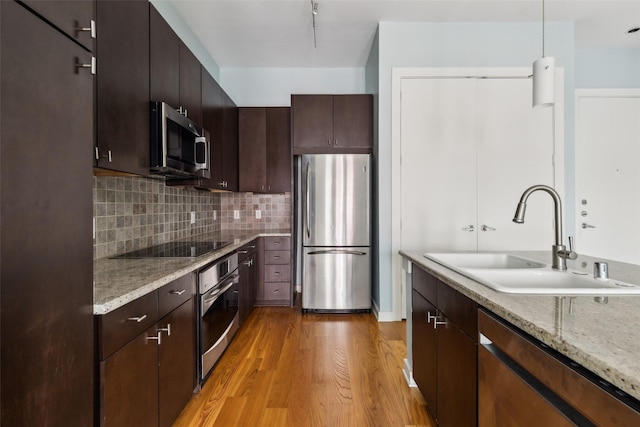 kitchen featuring a sink, dark brown cabinetry, light wood-style flooring, backsplash, and appliances with stainless steel finishes