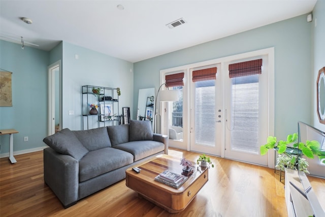 living room with wood finished floors, visible vents, and baseboards