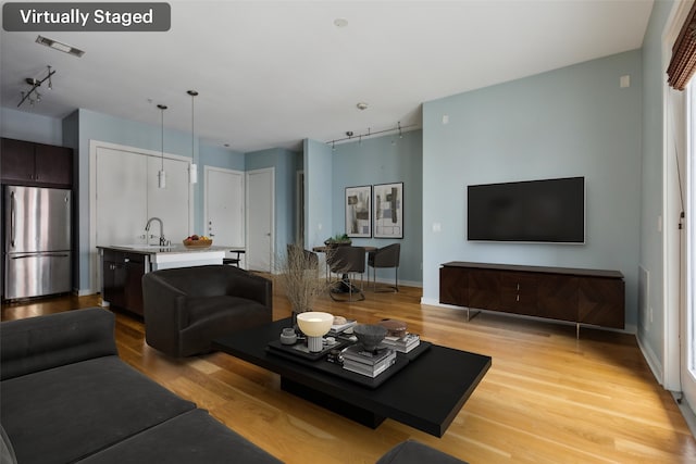 living room with rail lighting, visible vents, and light wood-style flooring