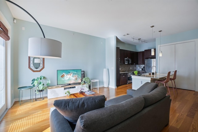 living area featuring track lighting, light wood-type flooring, and baseboards