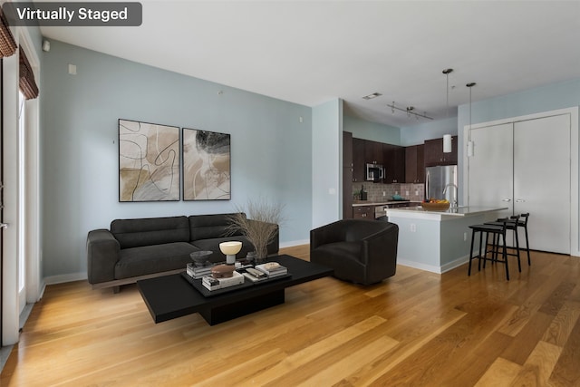 living room featuring visible vents, rail lighting, and light wood-type flooring
