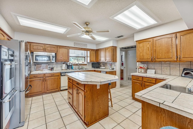 kitchen with visible vents, a breakfast bar area, appliances with stainless steel finishes, a sink, and light tile patterned flooring