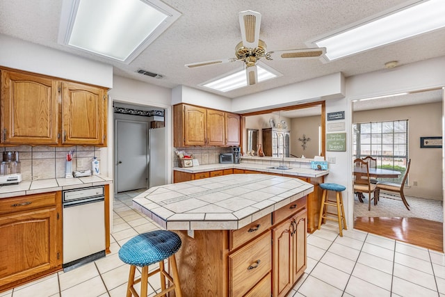 kitchen with brown cabinets, visible vents, tile countertops, and light tile patterned floors