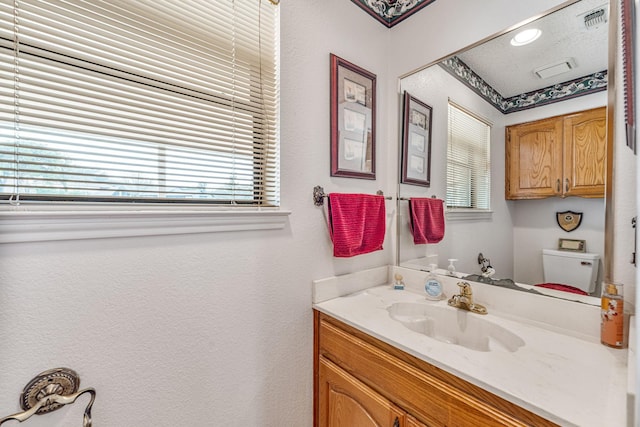 bathroom with visible vents, vanity, and toilet