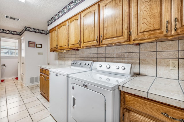 laundry area with cabinet space, visible vents, a textured ceiling, and independent washer and dryer