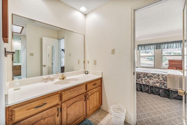 ensuite bathroom with a textured wall, ensuite bathroom, a textured ceiling, vanity, and tile patterned floors