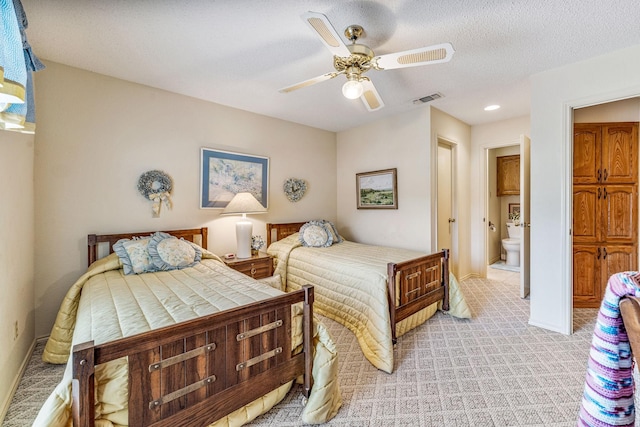 bedroom with ceiling fan, a textured ceiling, light colored carpet, visible vents, and baseboards