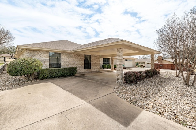 view of front facade with concrete driveway, a shingled roof, and fence