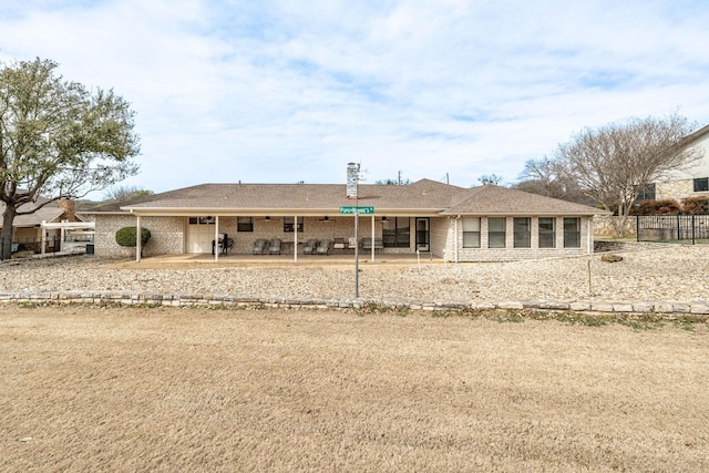 back of house featuring a garage, brick siding, a patio, and fence