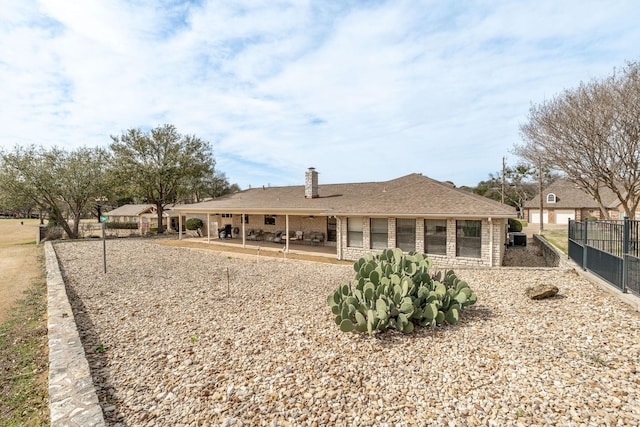 rear view of house with a chimney, fence, a patio area, central AC, and brick siding