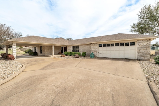 ranch-style home featuring roof with shingles, driveway, and an attached garage