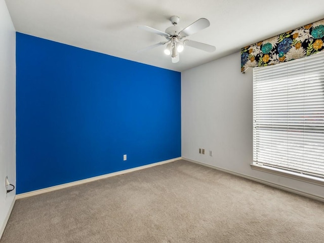 spare room featuring a ceiling fan, carpet flooring, and baseboards