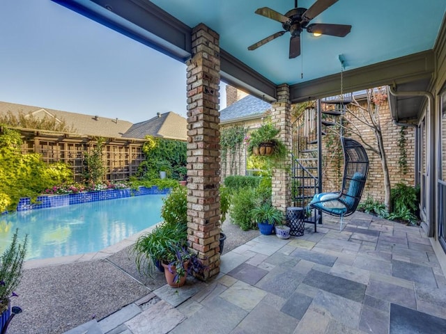 view of patio featuring ceiling fan, fence, and a fenced in pool