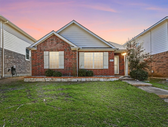 view of front of property featuring a lawn and brick siding