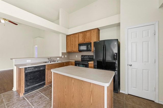 kitchen featuring black appliances, dark tile patterned flooring, a sink, and light countertops