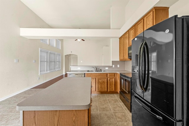 kitchen with black appliances, brown cabinetry, light tile patterned flooring, and a sink