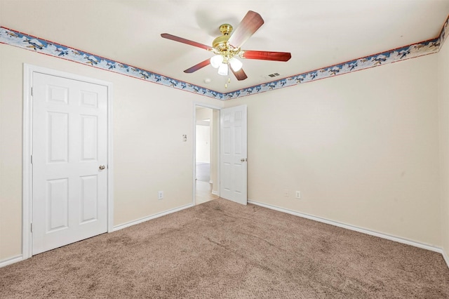 carpeted empty room with ceiling fan, visible vents, and baseboards