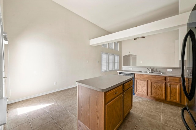 kitchen with light tile patterned floors, dishwasher, brown cabinets, freestanding refrigerator, and a sink