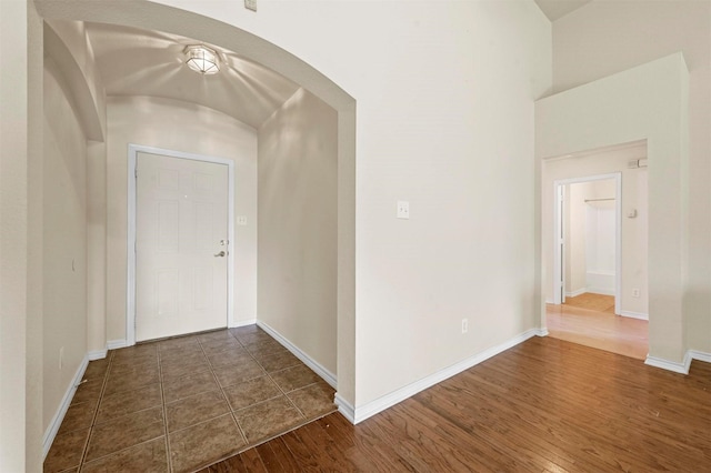 interior space featuring baseboards, arched walkways, and dark wood finished floors