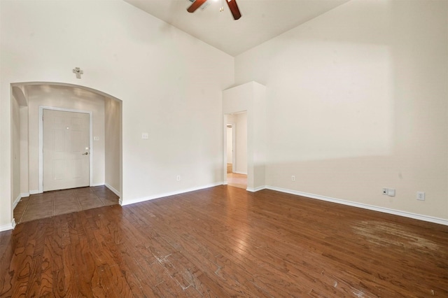 unfurnished room with arched walkways, baseboards, ceiling fan, wood finished floors, and high vaulted ceiling