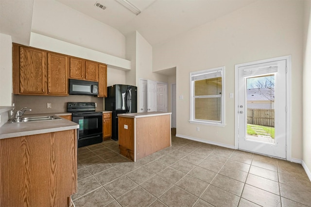 kitchen featuring visible vents, a kitchen island, black appliances, a sink, and light tile patterned flooring