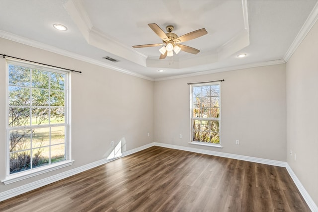 empty room with a tray ceiling, wood finished floors, and visible vents